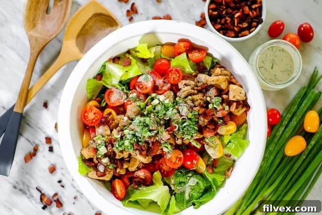 A large bowl of vibrant BLT salad, garnished with green onions and a generous drizzle of dressing. Utensils are placed beside it, inviting you to dig in.