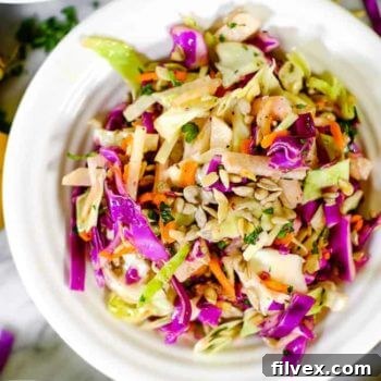 A vibrant bowl of Whole30 and Paleo compliant coleslaw, featuring shredded cabbage, carrots, and jicama, tossed in a zesty, mayo-free Italian dressing.