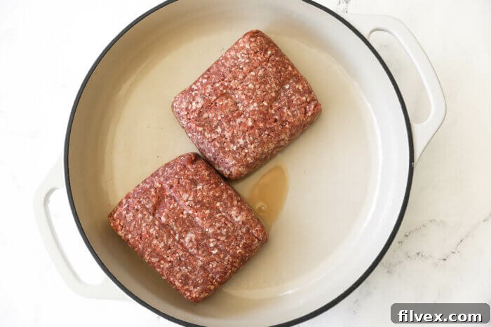 Two ground beef cubes in a white skillet