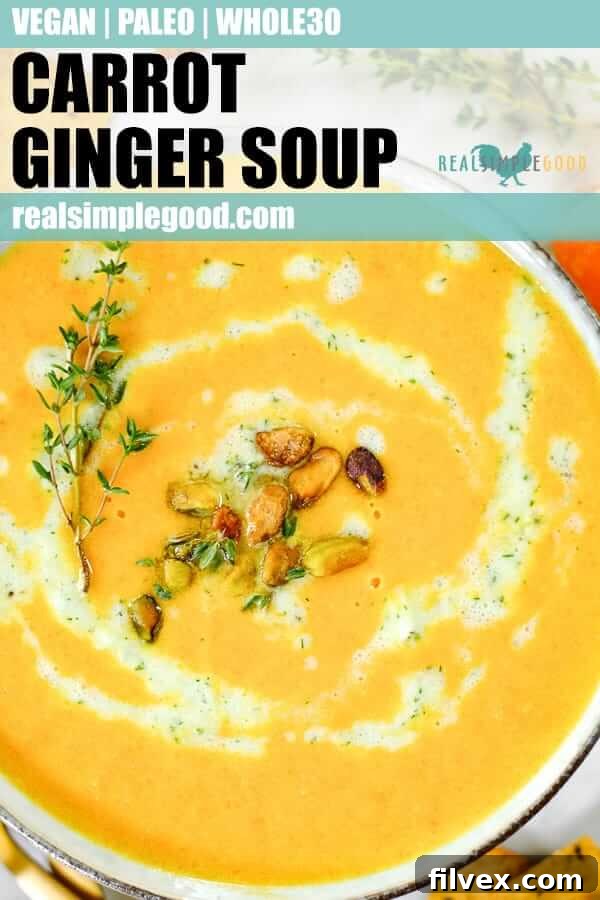 Long pin image of close-up shot of carrot ginger soup with tzatziki sauce, pistachios and fresh thyme.