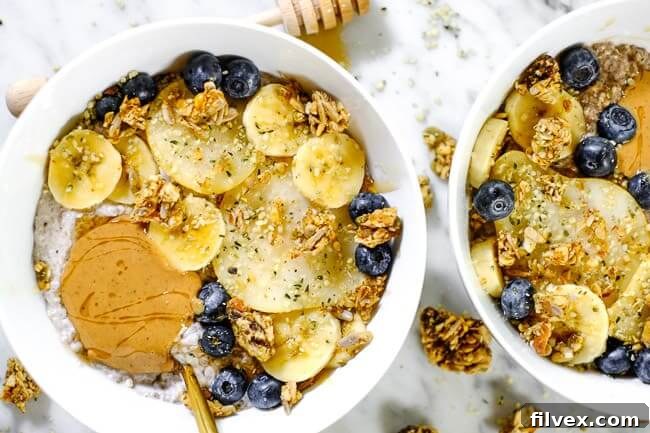 A beautifully styled bowl of Chai Spiced Paleo Chia Seed Pudding, topped with vibrant sliced bananas, juicy pears, fresh blueberries, crunchy grain-free granola, and a creamy swirl of nut butter, ready to be enjoyed.