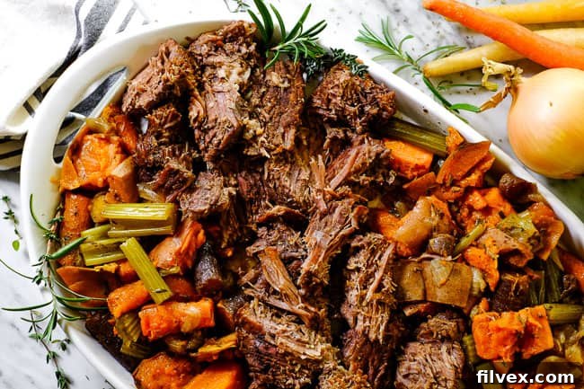 Instant Pot pot roast on a serving platter with sweet potato, carrots, onion, celery and fresh herbs. 