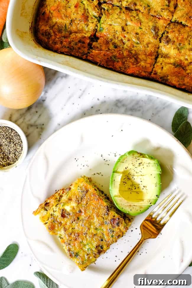 Overhead shot of Loaded Whole30 Breakfast Casserole on a plate with fresh avocado slices and a fork, emphasizing its ready-to-eat appeal.