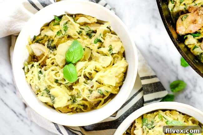 Creamy chicken casserole served in a bowl with fresh basil garnish and striped napkin. Highlighting the texture and appetizing presentation of the dairy-free, grain-free meal.