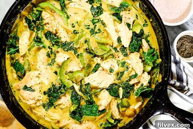 Thai coconut curry in cast iron skillet. Chicken, bell pepper, kale and onion in a creamy curry sauce.