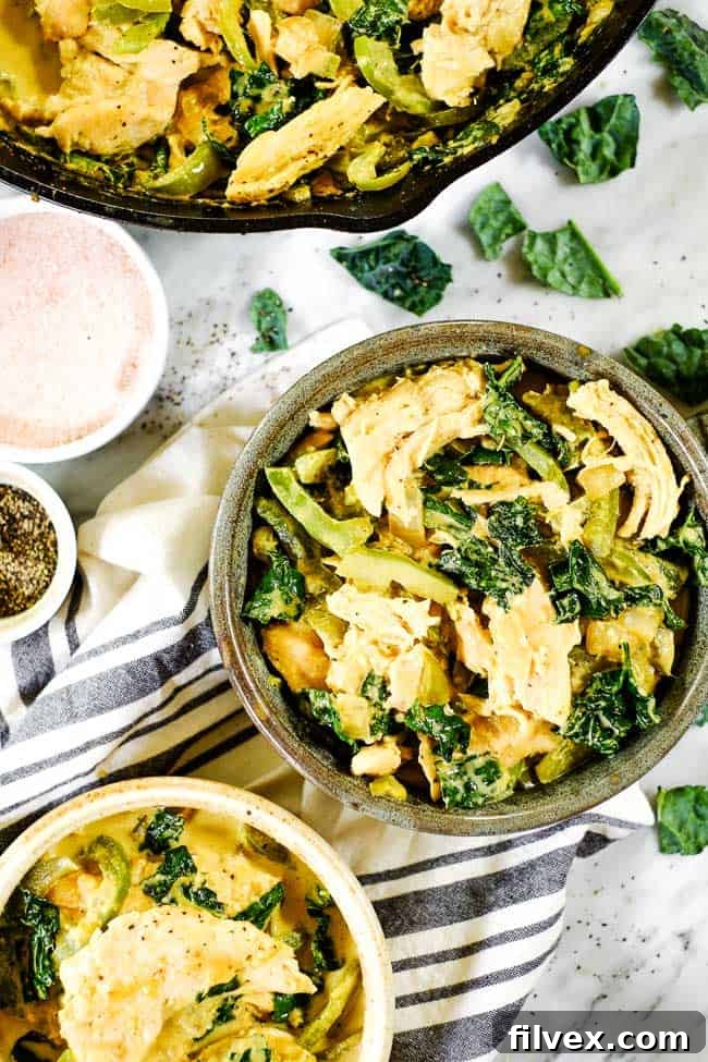 Thai coconut curry served in a bowl with extra skillet and a second bowl. Extra salt, pepper and kale on the table.