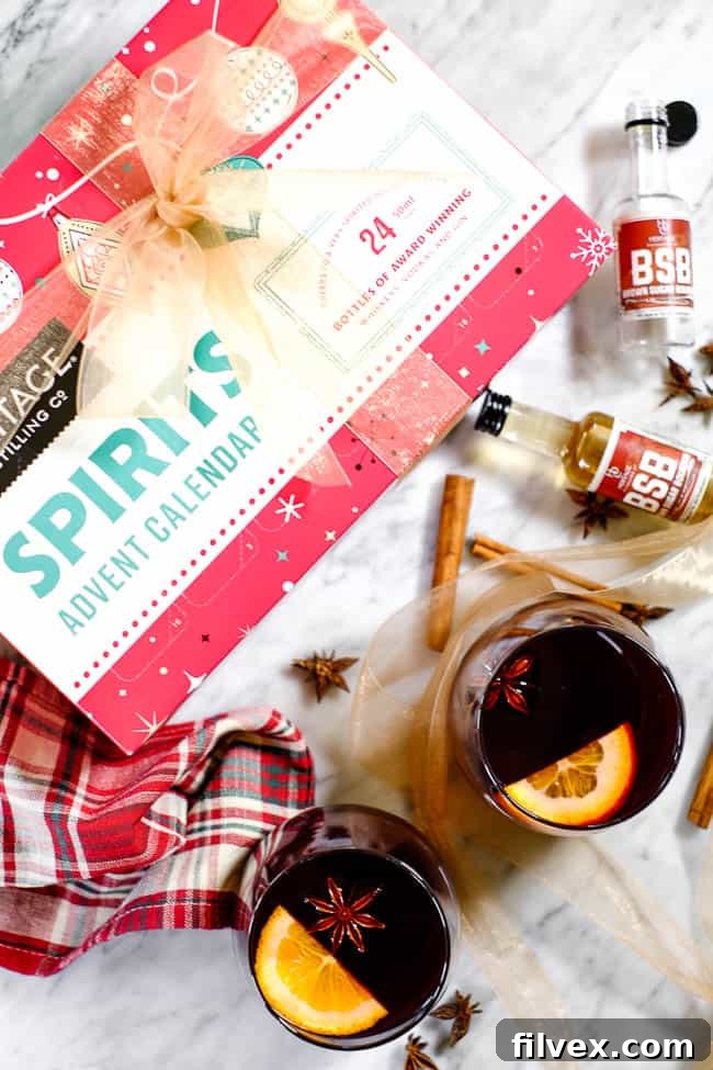 Simple mulled wine recipe in glasses with cinnamon sticks, orange slices, star anise, bourbon bottles and the Heritage Distilling Company 2018 advent calendar. 