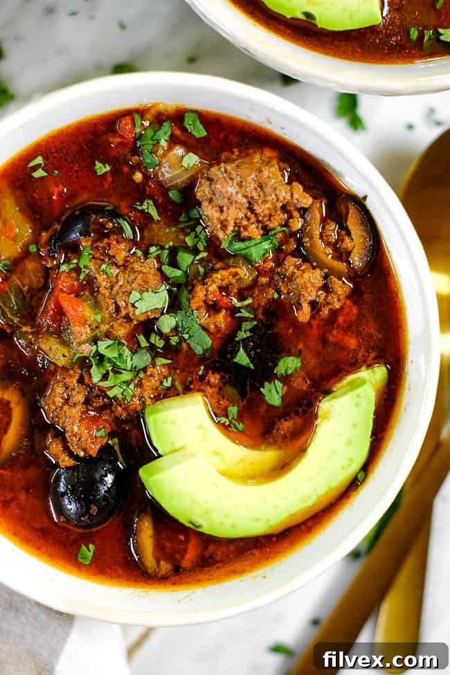 Close up of Instant Pot taco soup in a bowl with sliced avocado and chopped cilantro. 