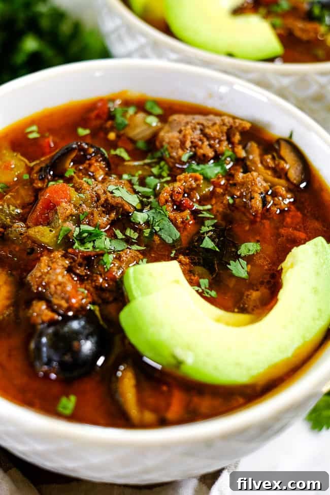 Angled shot of Instant Pot taco soup in bowl with sliced avocado and chopped cilantro. 