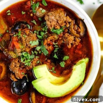 Close up of Instant Pot taco soup in a bowl with sliced avocado and chopped cilantro.