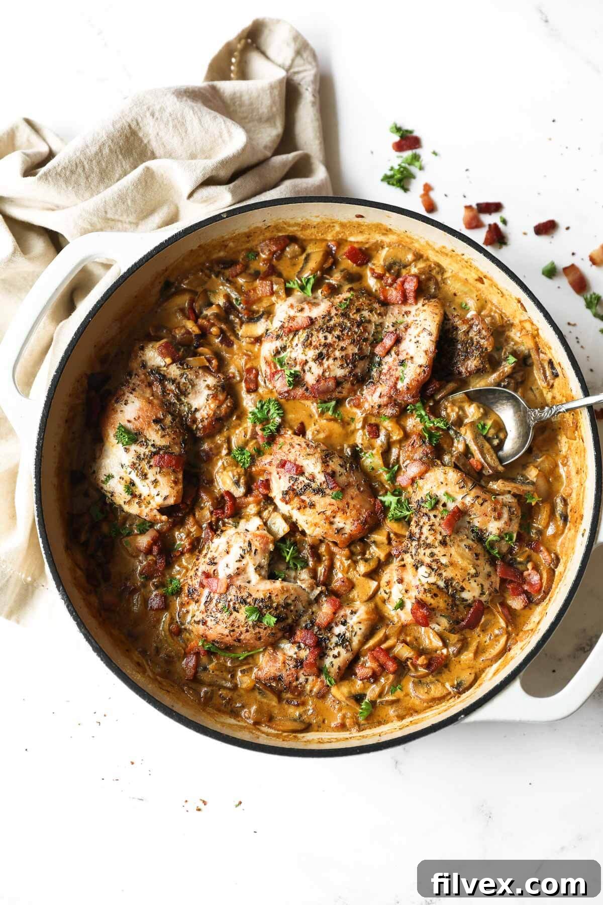 Close-up overhead shot of creamy garlic chicken in a skillet, garnished with fresh herbs and ready to serve.