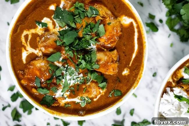 Instant pot butter chicken in a bowl with coconut milk drizzled on top and chopped fresh cilantro. 