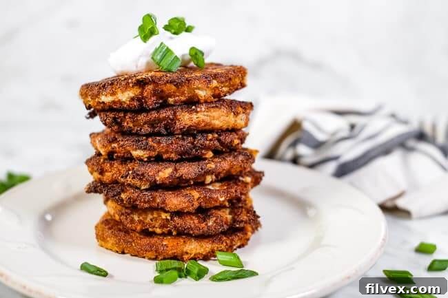 Stack of cauliflower fritters, topped with coconut yogurt and chopped green onion.