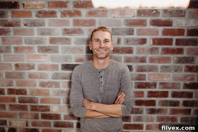 Man smiling confidently in front of a brick background, symbolizing success and positive results from intermittent fasting.