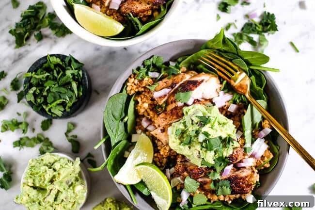 A vibrant chicken burrito bowl served with fresh cilantro, creamy guacamole, and zesty lime wedges on the side, ready to be enjoyed.