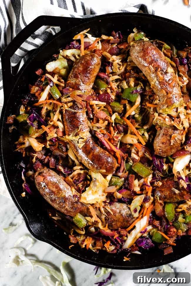 Sausage and cabbage skillet simmering in a large cast iron skillet.