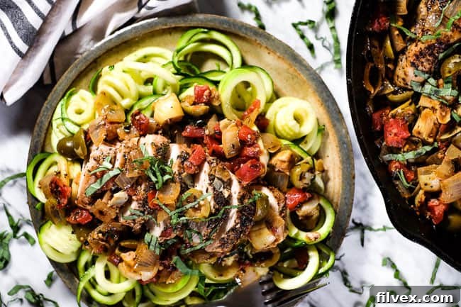 Flavorful Chicken in Tomato Sauce served elegantly on a plate over a bed of zoodles, garnished with fresh basil for a vibrant, healthy meal. 