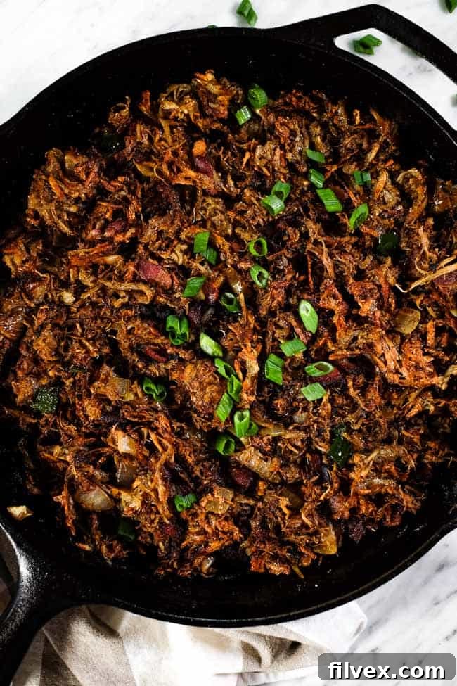 A hearty serving of Leftover Pulled Pork Hash in a rustic black skillet, ready to be enjoyed.