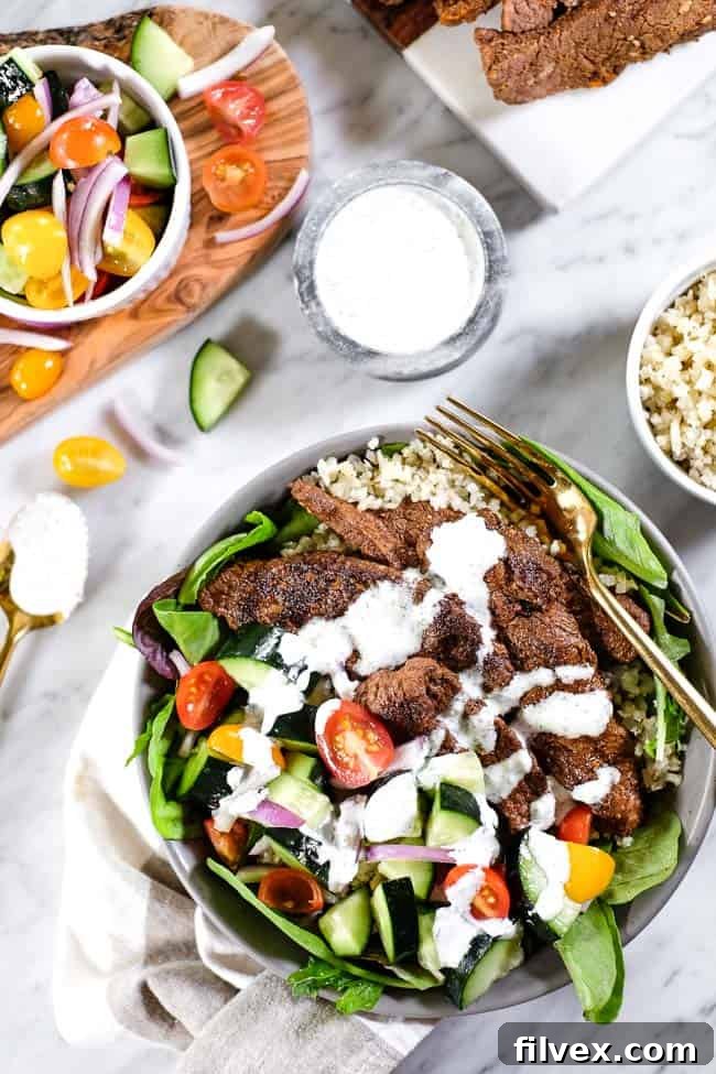 Close-up of the dairy-free tzatziki sauce drizzled over a Beef Shawarma Bowl, showing its creamy texture and fresh ingredients.