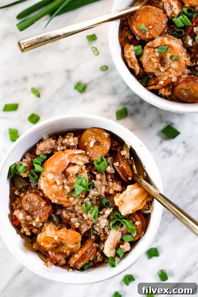 A beautifully presented bowl of Instant Pot Jambalaya, adorned with chopped green onions and a fork, highlighting its rich textures.