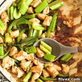 Overhead shot of half full pan of black pepper chicken stir fry with celery and bell pepper