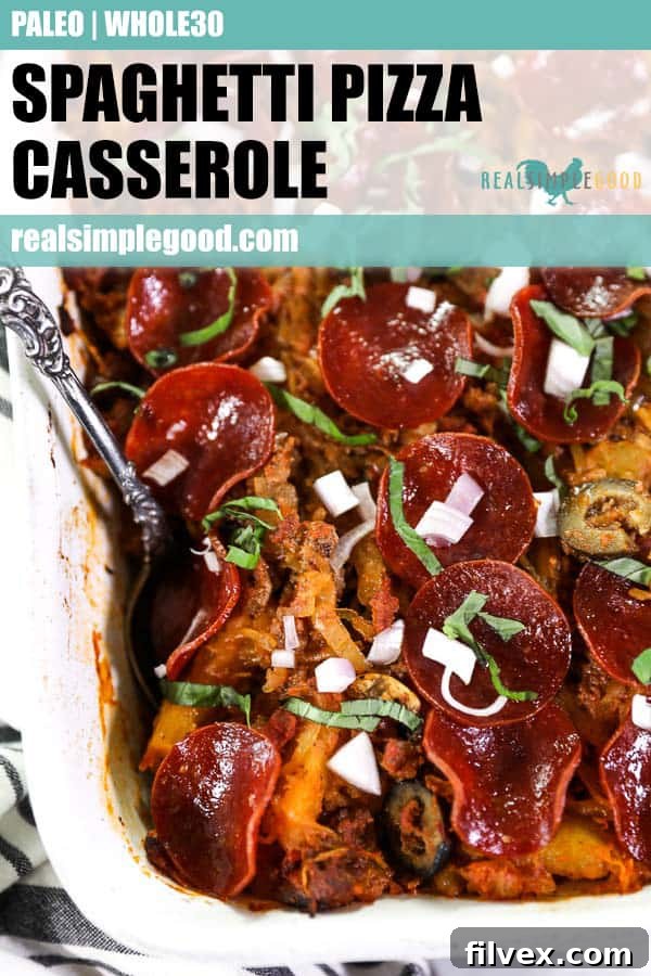 Close up shot of spaghetti pizza casserole in dish with serving spoon and topped with chopped red onion and basil. 