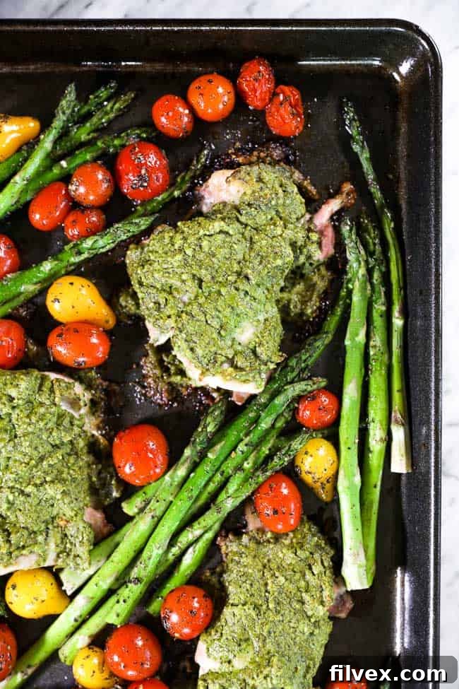 Easy baked pesto chicken on sheet pan with tomatoes and asparagus close up image