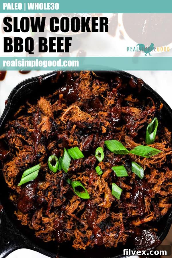 A close-up of slow cooker BBQ beef in a cast iron skillet, garnished with fresh BBQ sauce and chopped green onions.