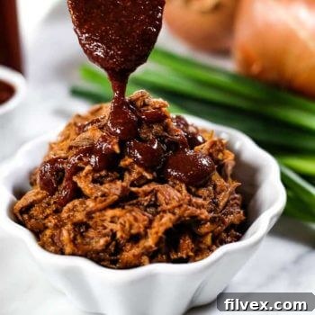Homemade Whole30 BBQ sauce being drizzled over slow cooker BBQ beef.