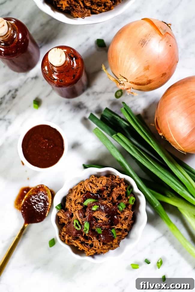 A small ramekin filled with slow cooker BBQ beef, generously topped with more BBQ sauce and fresh chopped green onions. Additional sauce and onions are visible in the background on a wooden table.