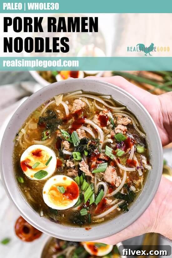 Pork ramen noodles served in a bowl and topped with chopped green onion, a soft boiled egg and hot sauce. 