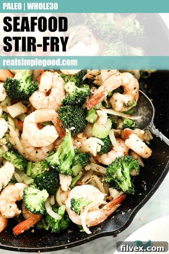 Close-up of a sizzling Paleo and Whole30 seafood stir-fry in a cast iron skillet, featuring shrimp, white fish, broccoli, celery, and onion, generously seasoned with Cajun spices. The image is overlaid with text optimized for Pinterest sharing, encouraging readers to save the recipe.