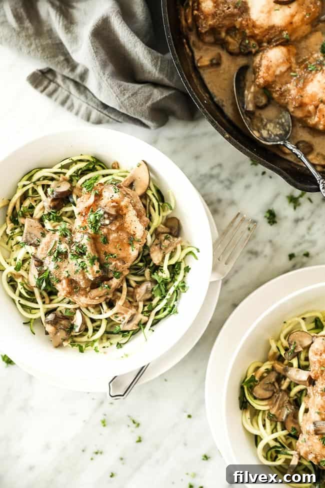 Easy chicken marsala with chicken, mushrooms and a creamy sauce served in a bowl over zucchini noodles with a fork on the side. Fresh chopped parsley sprinkled on top. 