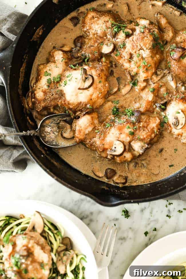 Easy chicken marsala with chicken, mushrooms and a creamy sauce in a cast iron skillet. Fresh chopped parsley sprinkled on top. 