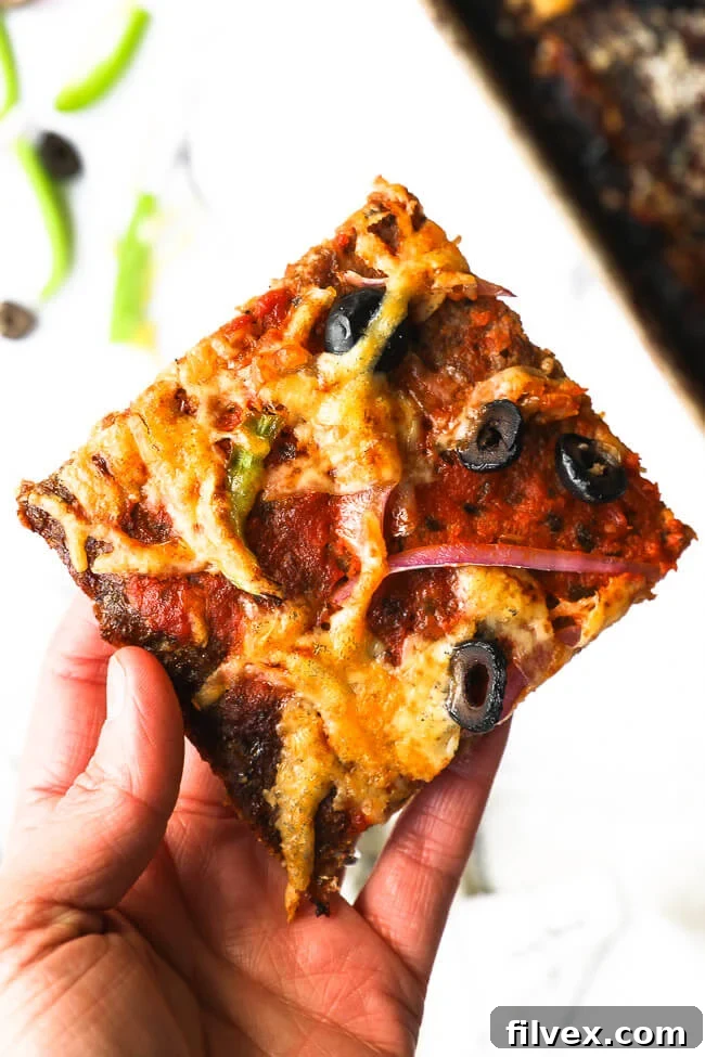 Holding one slice of keto meatza. 