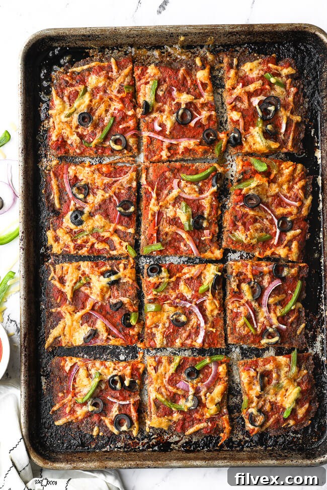 Overhead image of sheetpan with meatza cut into square slices. 