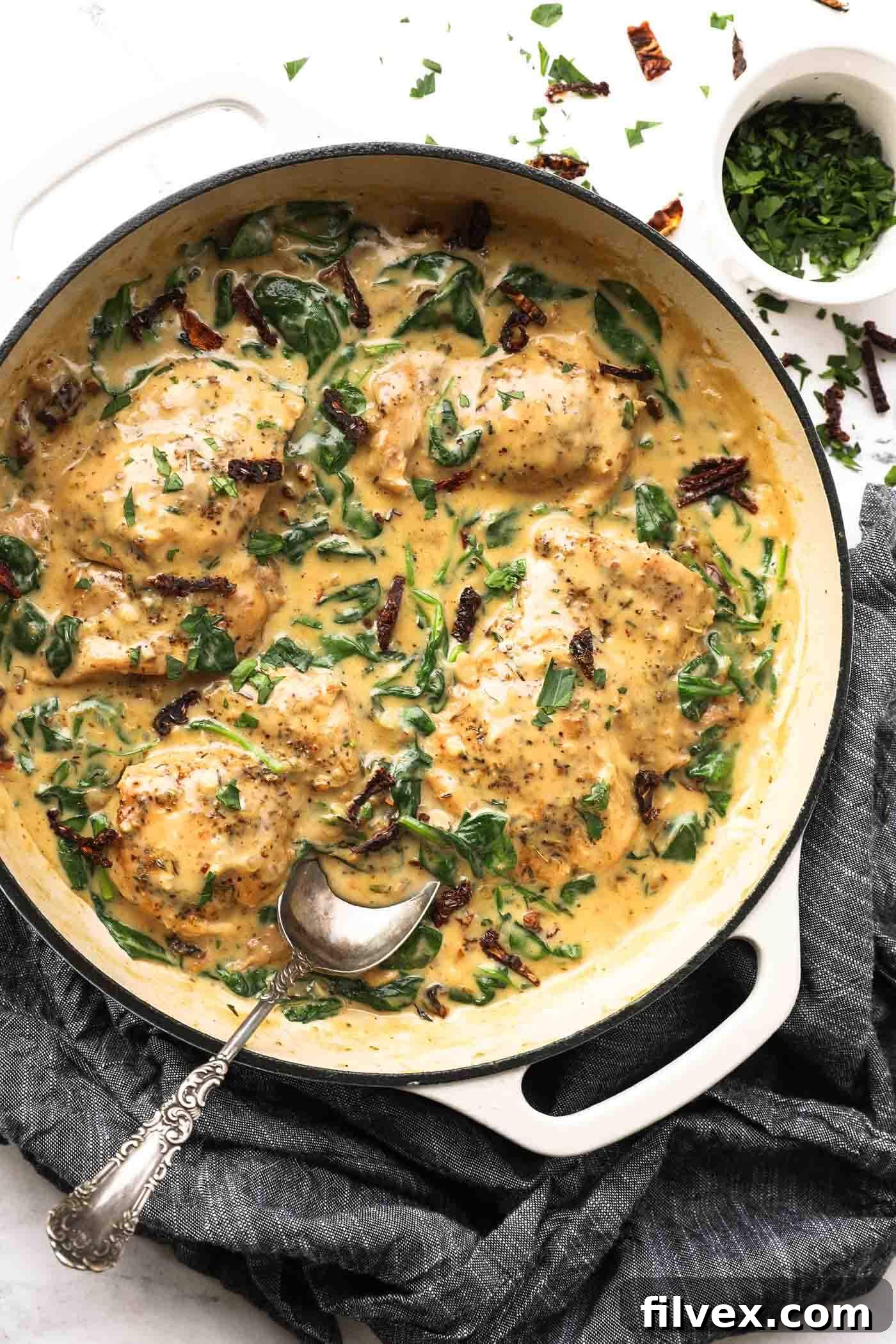 Overhead shot of creamy Tuscan chicken in a skillet, garnished with fresh basil.