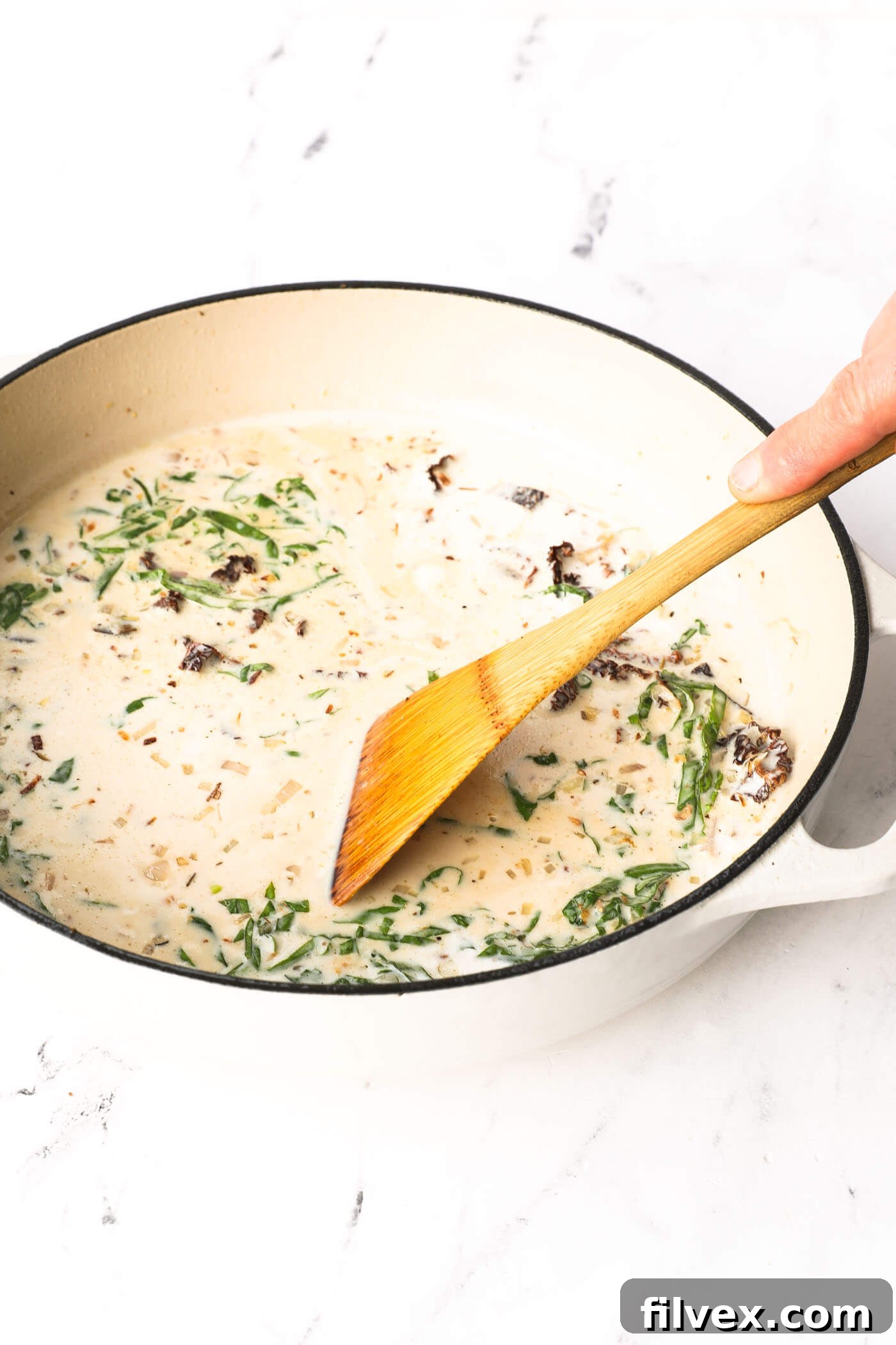 Sauce in the skillet being stirred, scraping up browned bits.