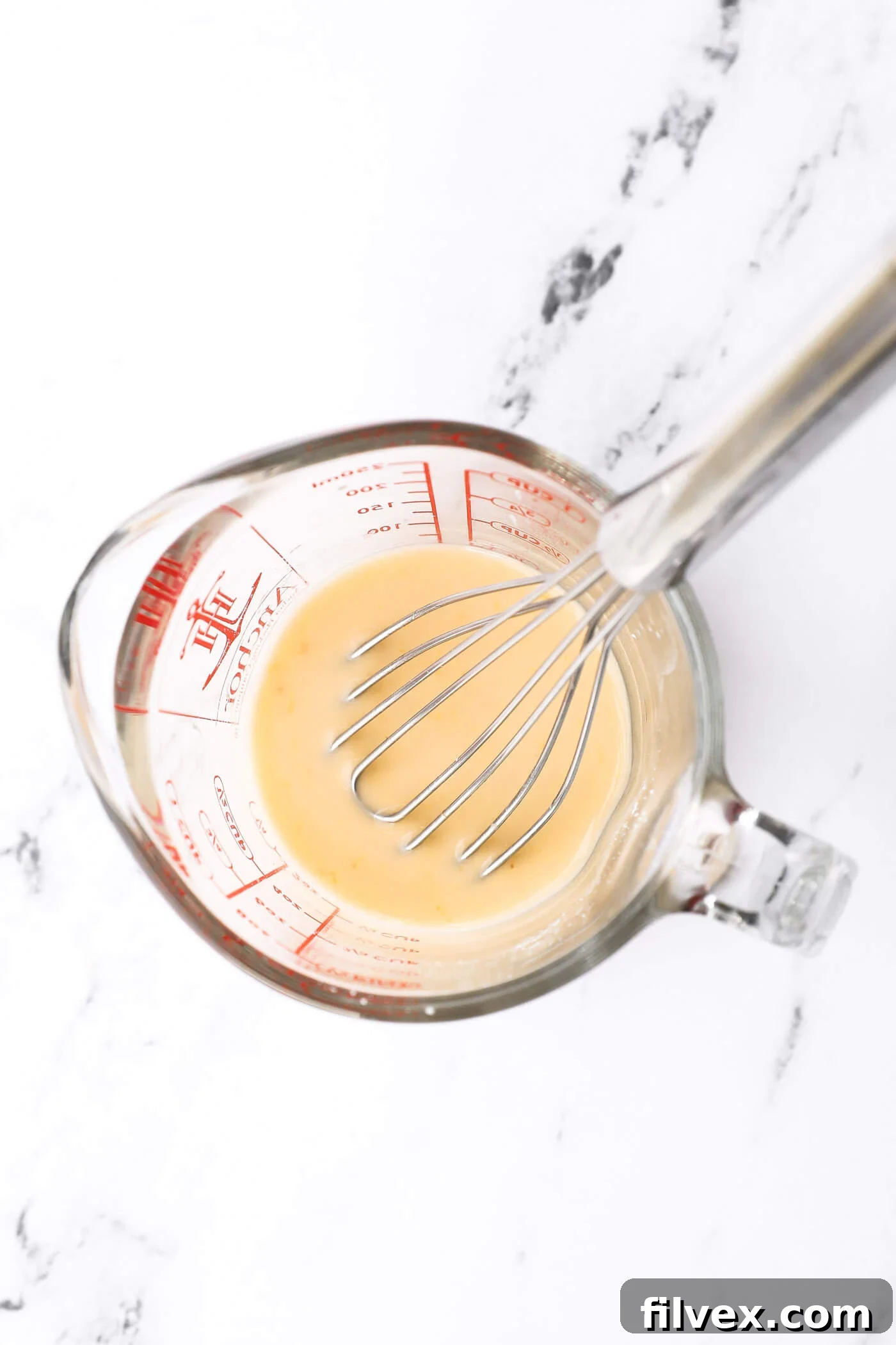 Chicken broth and starch being whisked together in a bowl.