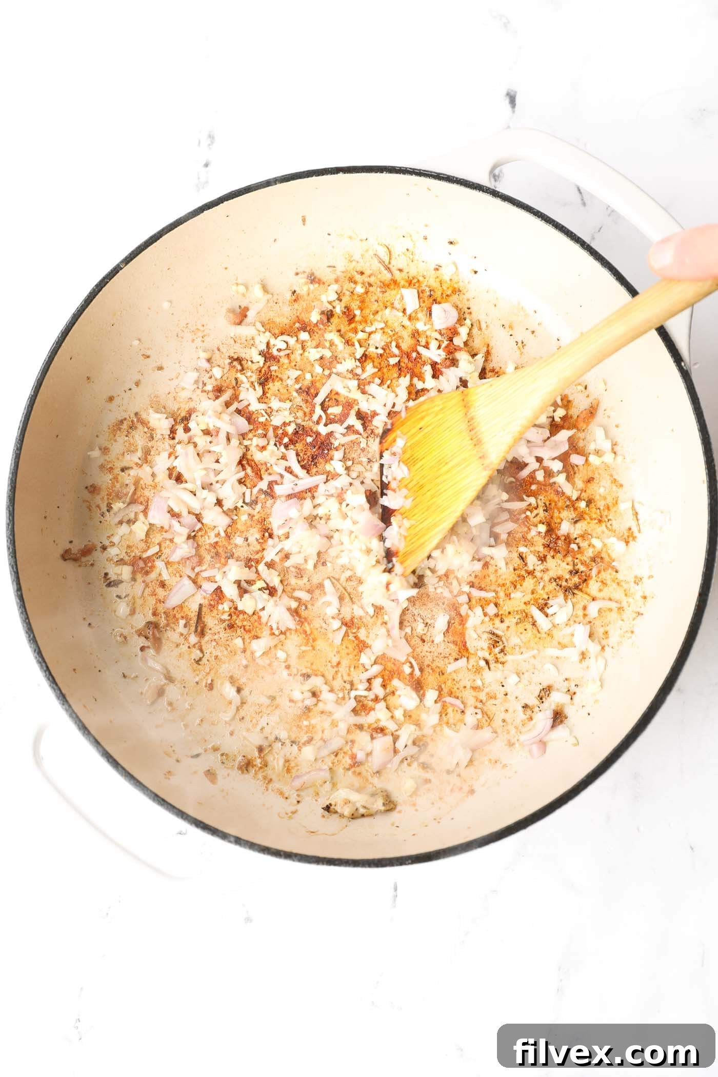 Shallots and garlic sautéing in a skillet with ghee.