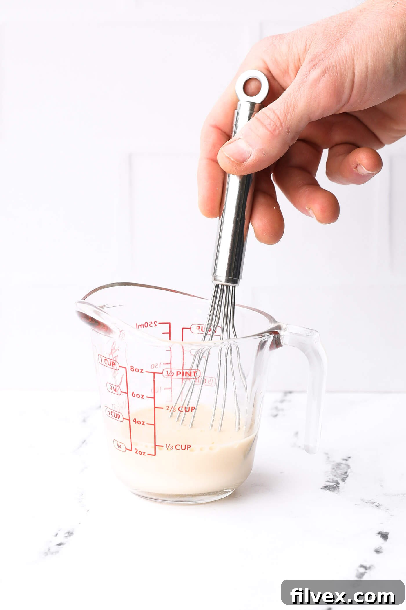 Chicken broth and starch mixture being poured into the skillet with the sauce ingredients.