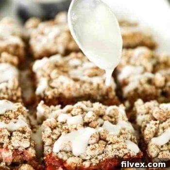 A beautifully presented image of baked strawberry crumble bars, garnished with a luxurious coconut butter drizzle.