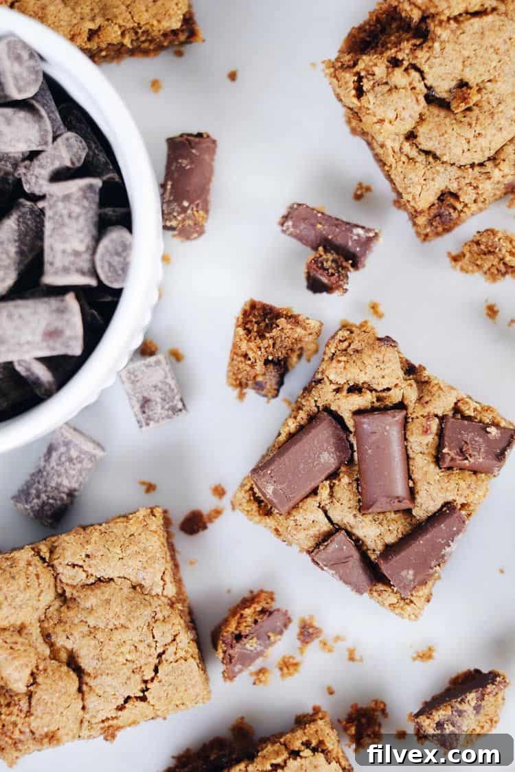 A delectable image of perfectly portioned chocolate chip cookie bars, showcasing their golden-brown edges and gooey, chocolate-filled centers. A scattering of chocolate chips on top suggests a rich, sweet experience.