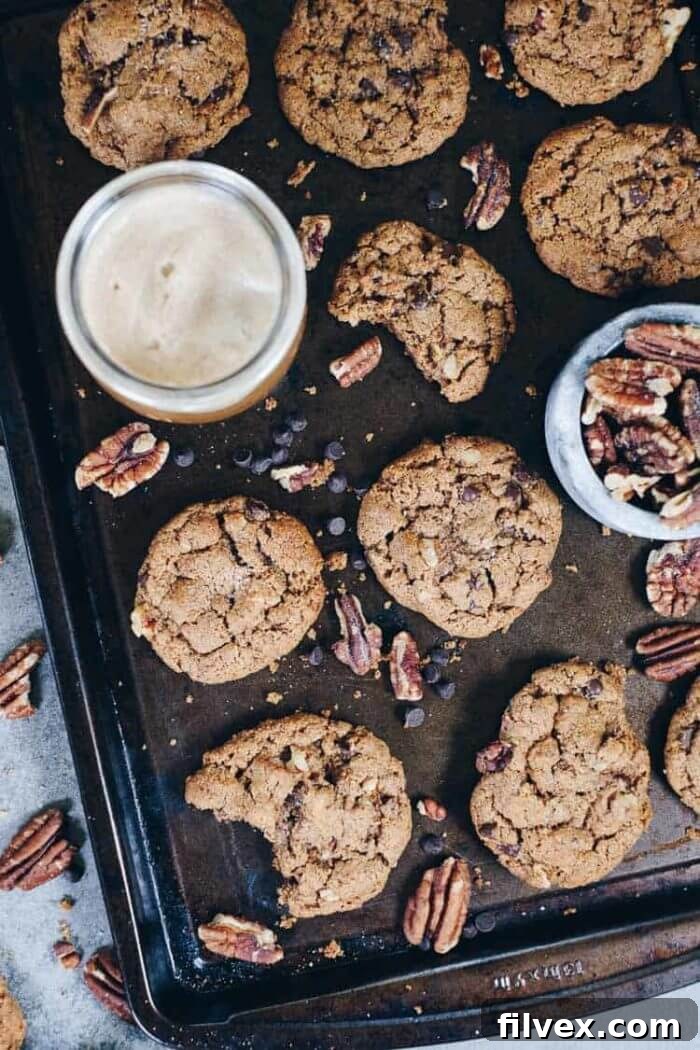 An enticing shot of freshly baked chocolate chip pecan cookies, with visible chunks of chocolate and crunchy pecans. Their rustic, homemade appearance promises a comforting and flavorful bite.