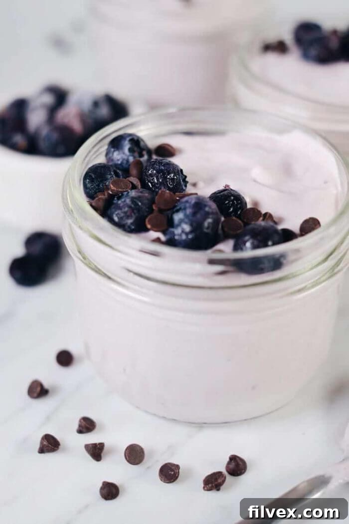 A light and airy image of an easy berry mousse, presented in an elegant glass, topped with fresh berries. The vibrant colors and smooth texture suggest a refreshing and sophisticated dessert.