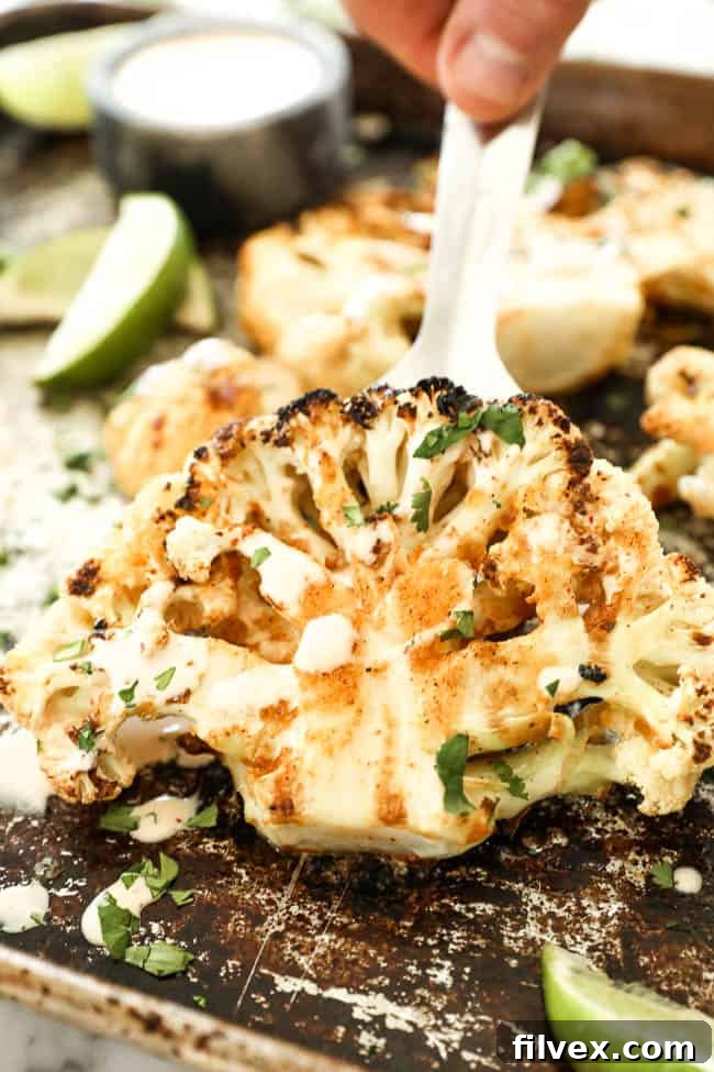 Lifting cauliflower steak off cooking sheet with a spatula. 