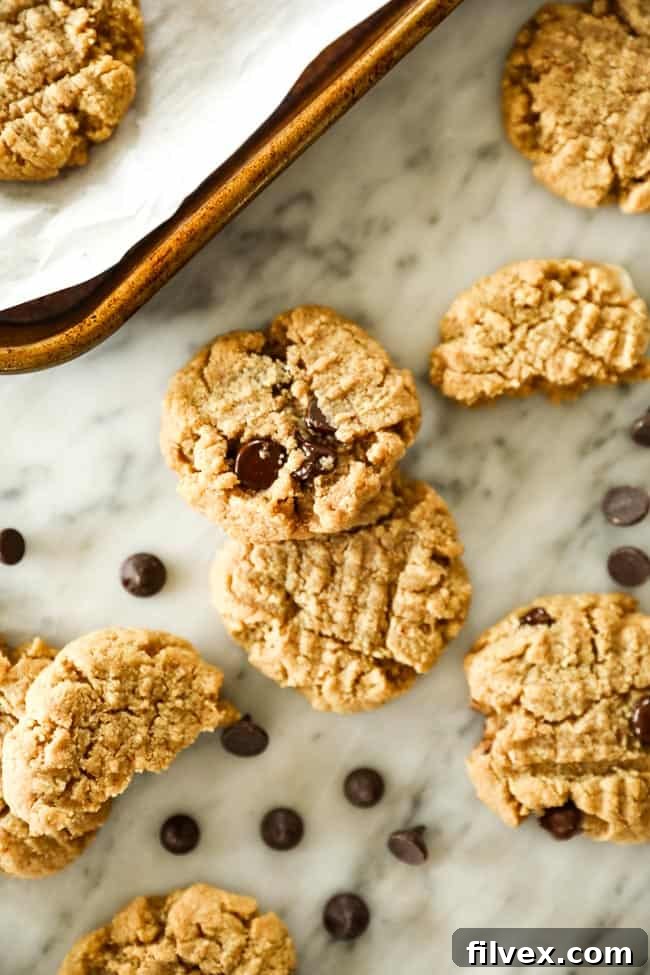 Low carb cookies with no sugar added chocolate chips spread out on marble with chocolate chips sprinkled about. 