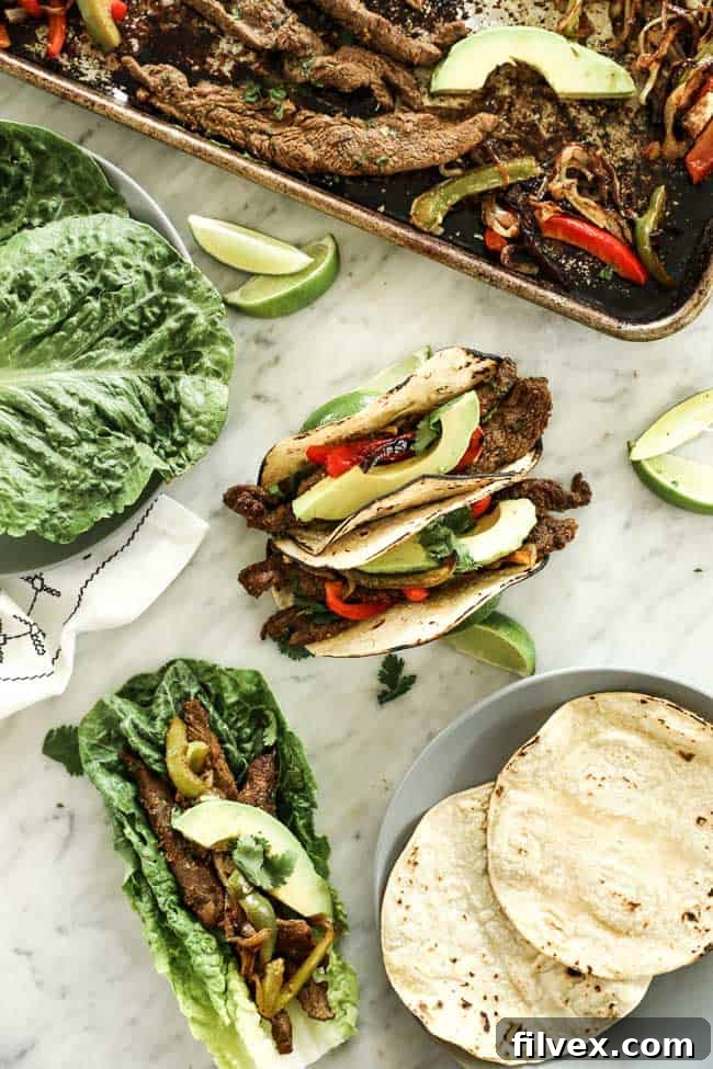 Vertical overhead image of sheet pan fajitas served in soft taco shells and also in romaine lettuce leaves. Topped with sliced avocado and fresh cilantro. 