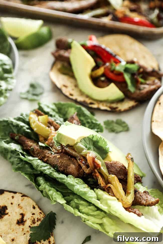 Angled image of sheet pan fajitas in romaine lettuce leaves with avocado and cilantro on top. 