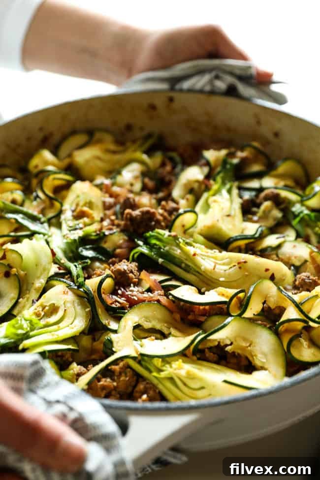 Close-up of Szechuan noodles in a skillet, showcasing the rich sauce, ground beef, and colorful vegetables.